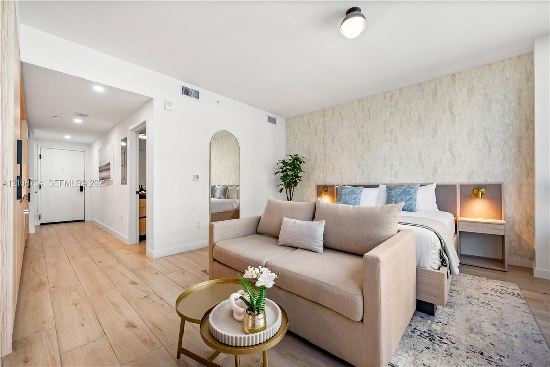Wood-finish flooring, textured accent wall, integrated headboard with built-in side tables, arched floor mirror, and recessed ceiling lighting