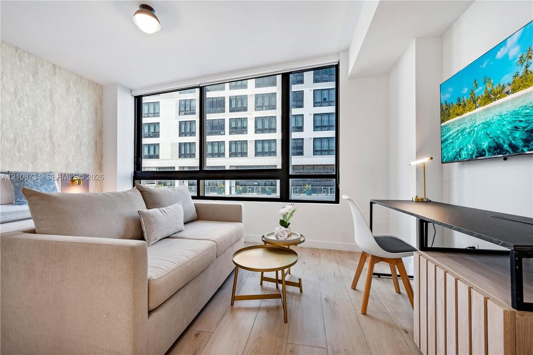 Wood-finish flooring, floor-to-ceiling black-framed windows, and textured accent wall