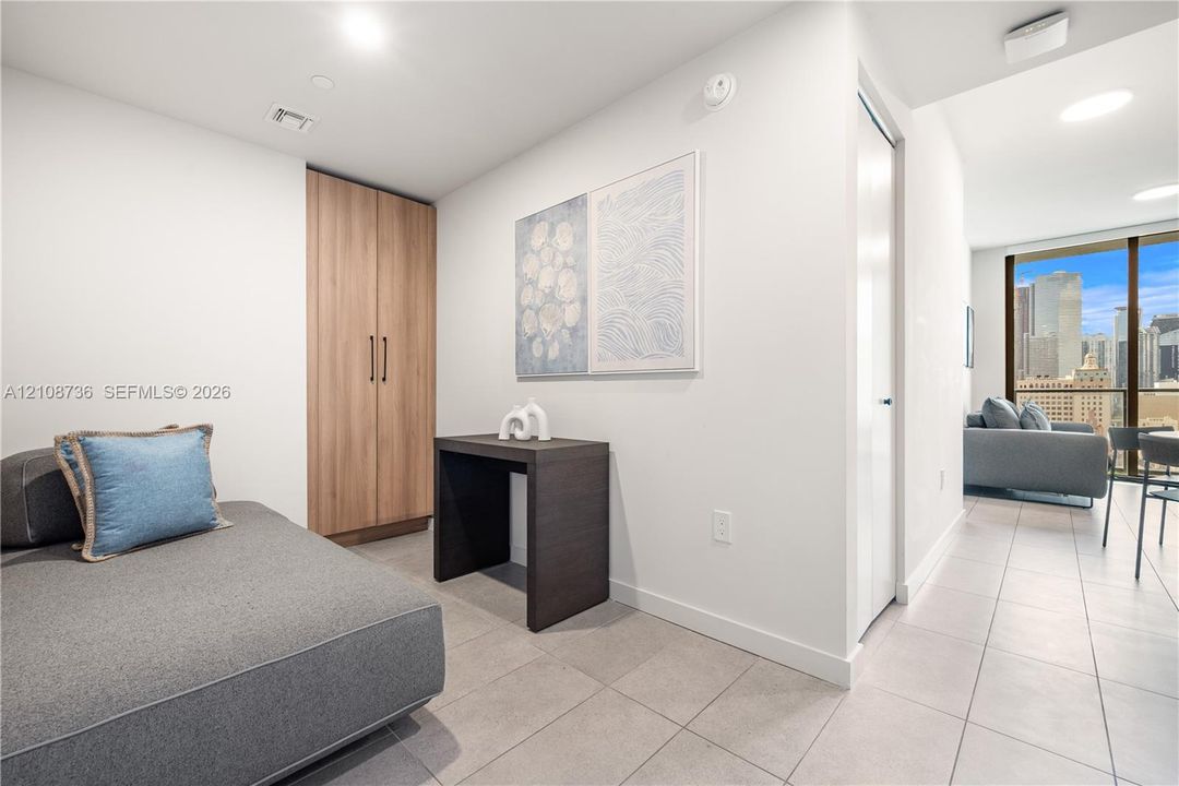 Floor-to-ceiling windows with urban skyline exposure, tile flooring, and a floor-to-ceiling wooden cabinetry unit