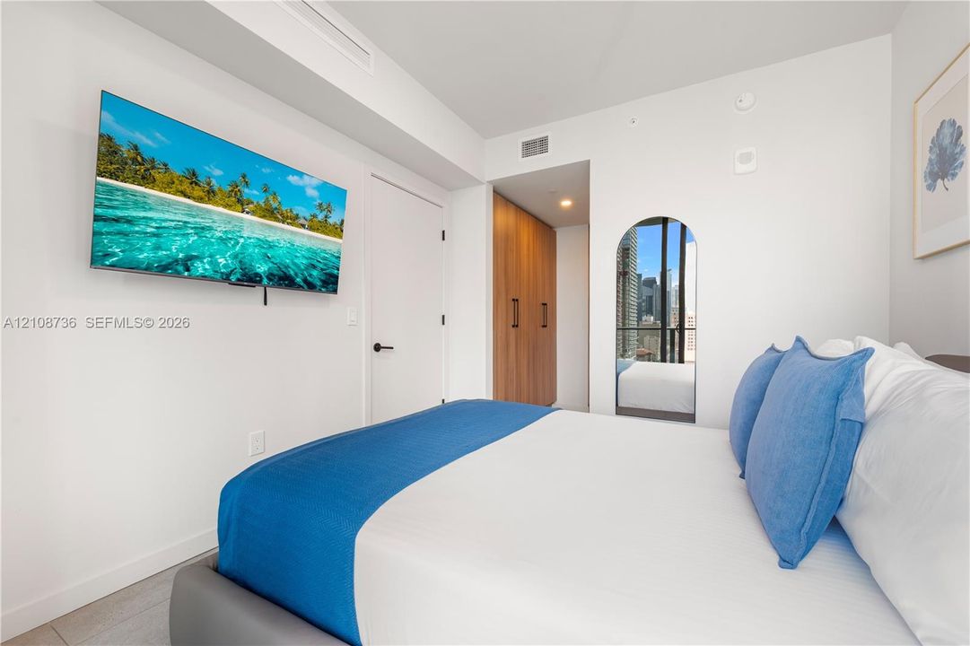 Room featuring an arched full-length mirror, wood-finish built-in cabinetry, and neutral wall-finish flooring