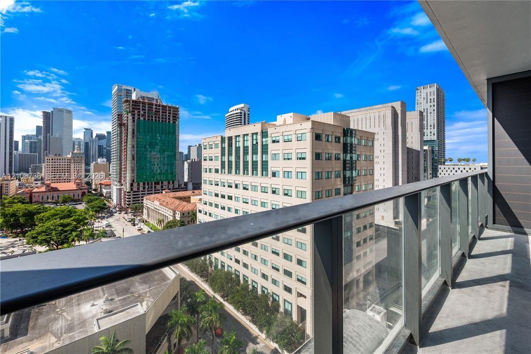Private balcony featuring a glass panel railing, metal top rail, and concrete flooring