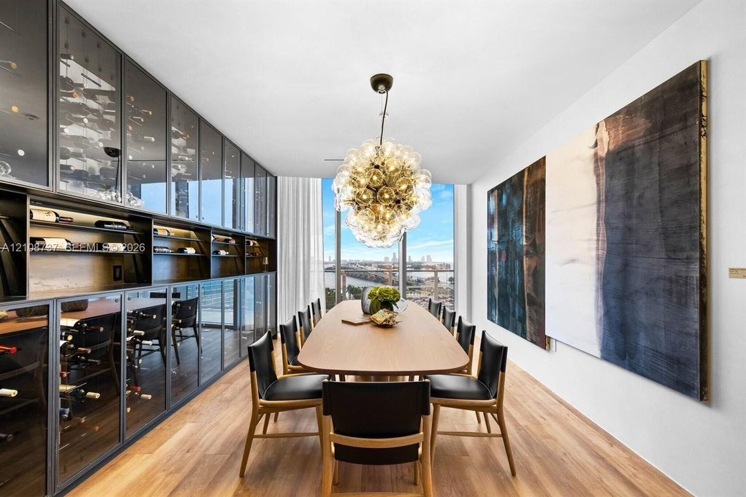 Built-in floor-to-ceiling glass-front cabinetry with integrated shelving, wood-finish flooring, multi-globe chandelier, and expansive windows