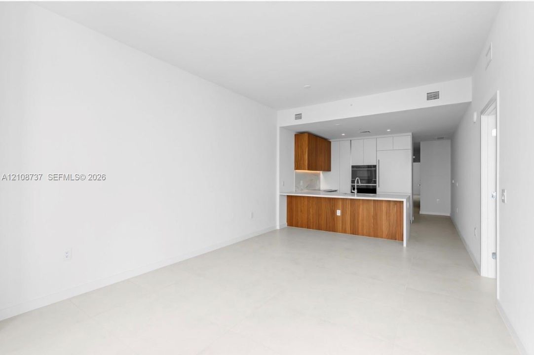 Kitchen featuring two-tone cabinetry, wood-finish lower cabinets, integrated wall oven, and light-toned tile flooring