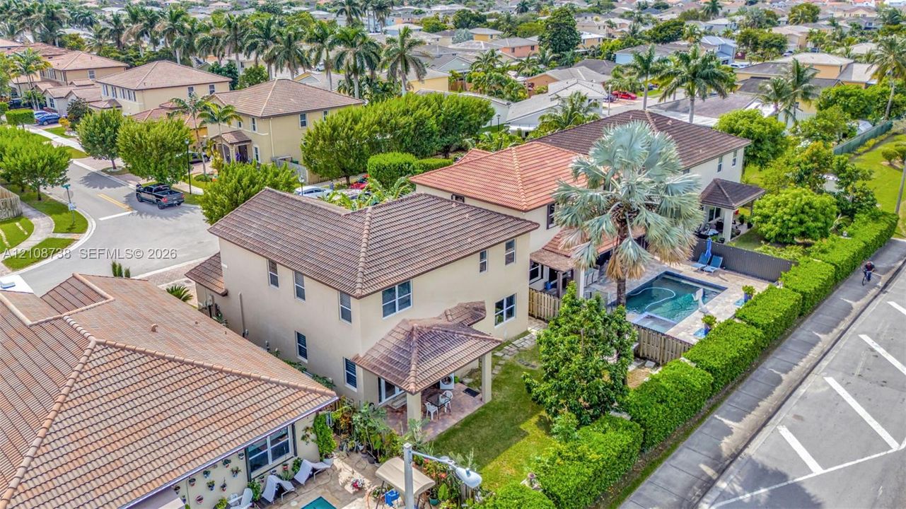 Two-story residence featuring a tile roof, an in-ground swimming pool, a paved patio, and mature landscaping