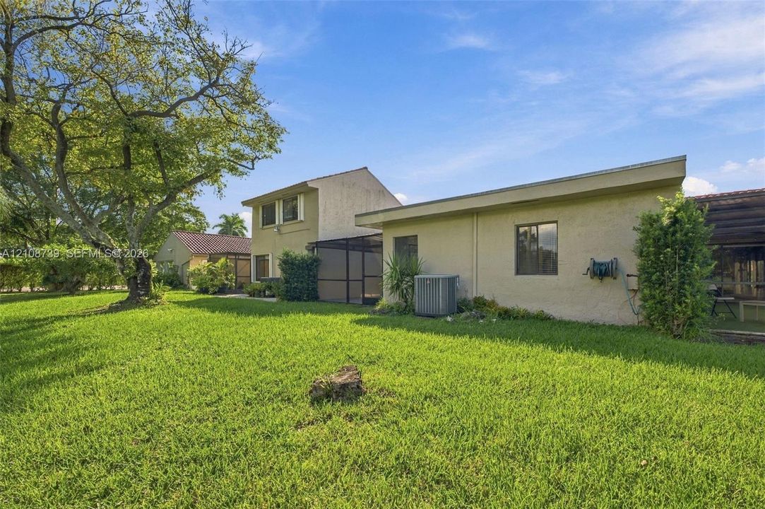 Expansive backyard featuring a large open lawn, mature specimen tree, and attached screened-in enclosure