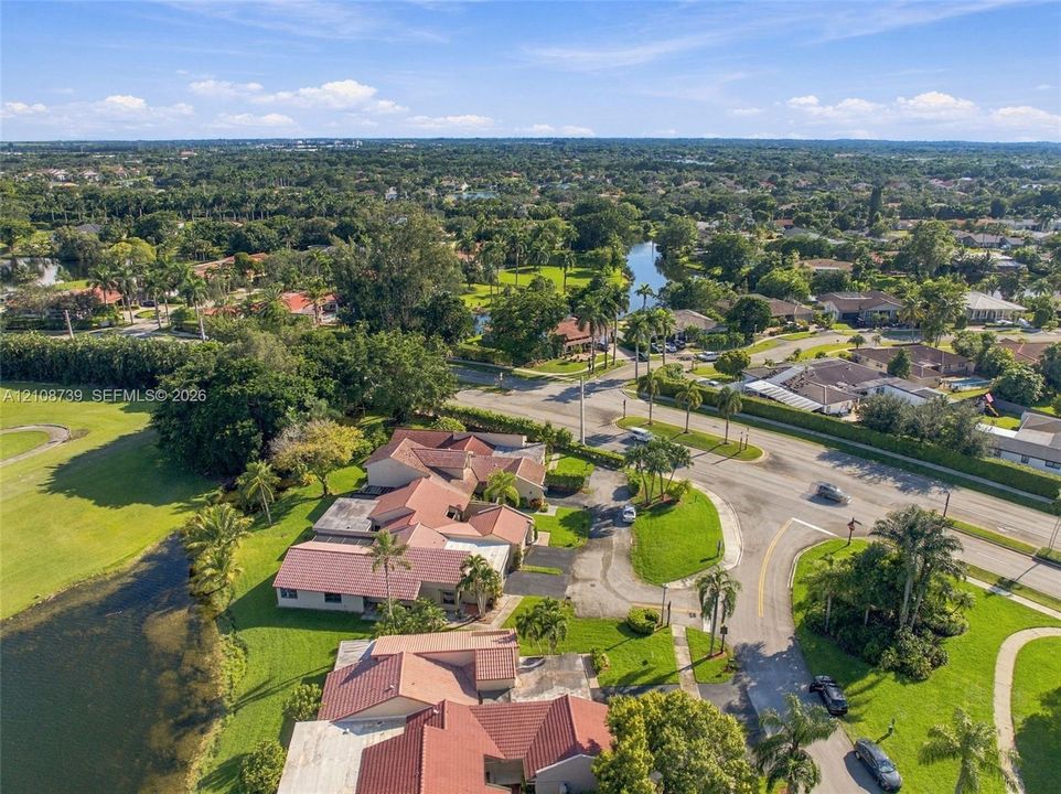 Aerial perspective featuring multi-gabled tile roofing, waterfront positioning, expansive lawn areas, and mature landscaping