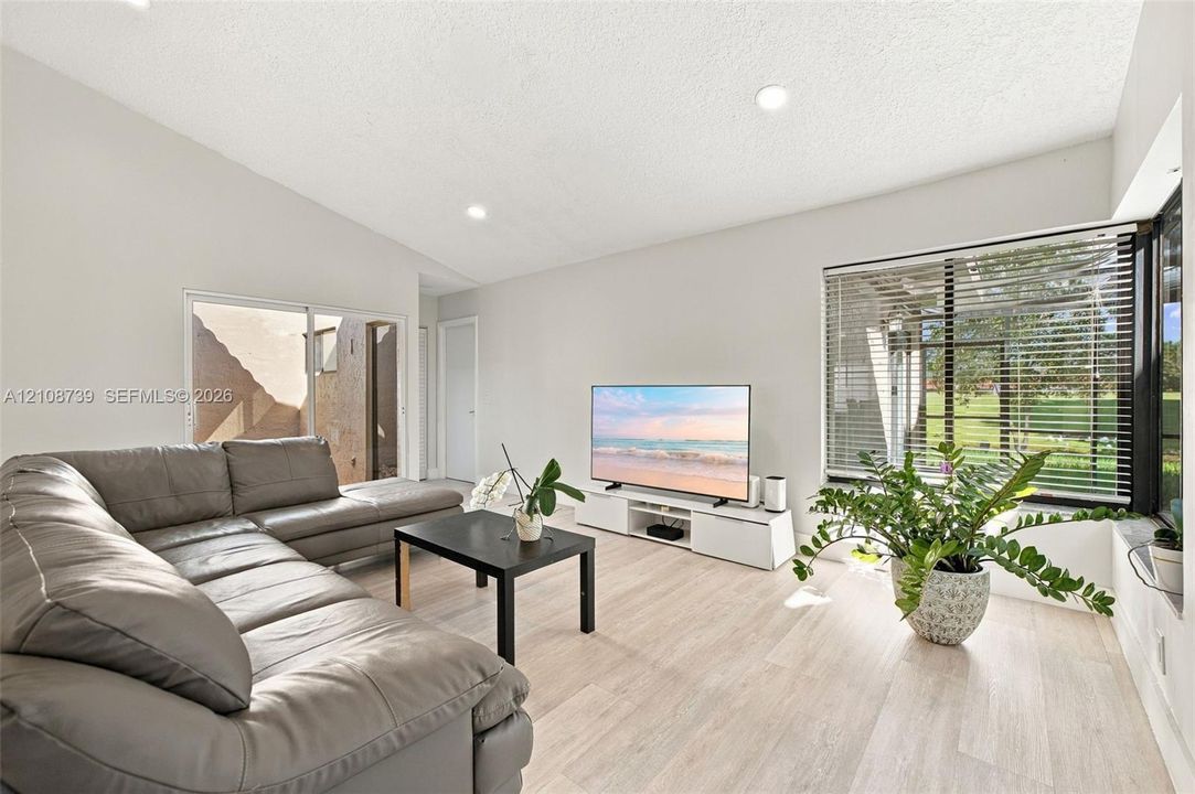 Vaulted ceilings, wood-finish flooring, recessed lighting, and expansive windows featuring horizontal blinds