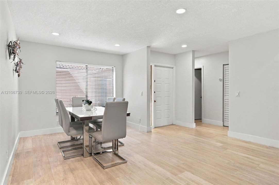 Open living space featuring wood-finish flooring, recessed lighting, and a multi-panel entry door