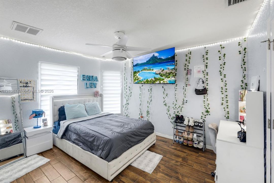 Room featuring wood-finish flooring, white ceiling fan, and dual-pane windows with horizontal blinds