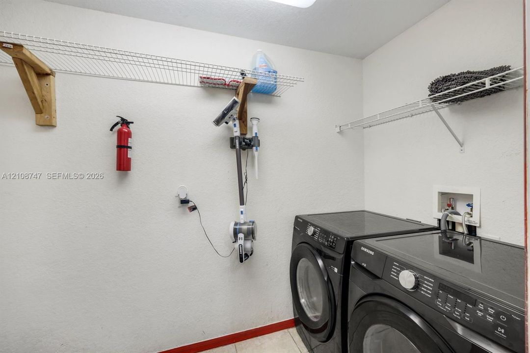 Laundry room featuring wall-mounted wire shelving, recessed laundry hookups, and tiled flooring