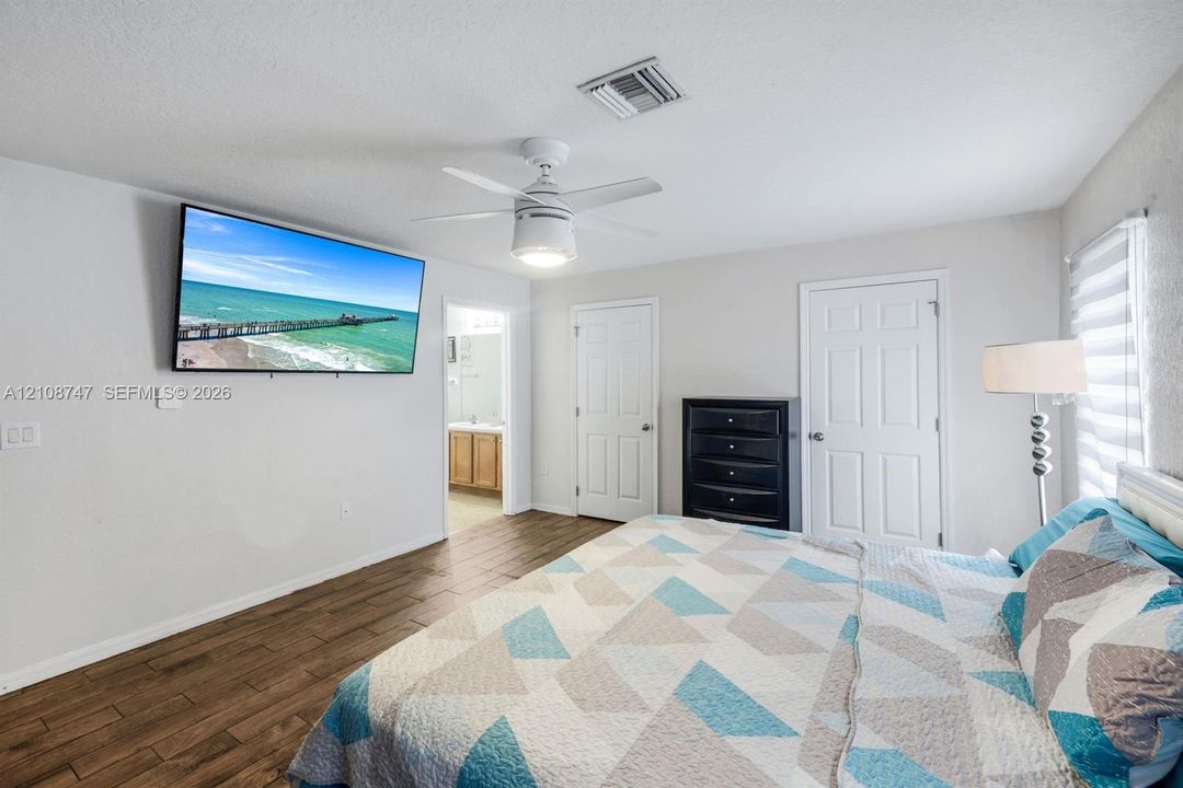 Wood-finish flooring, ceiling fan with integrated lighting, and multi-panel interior doors