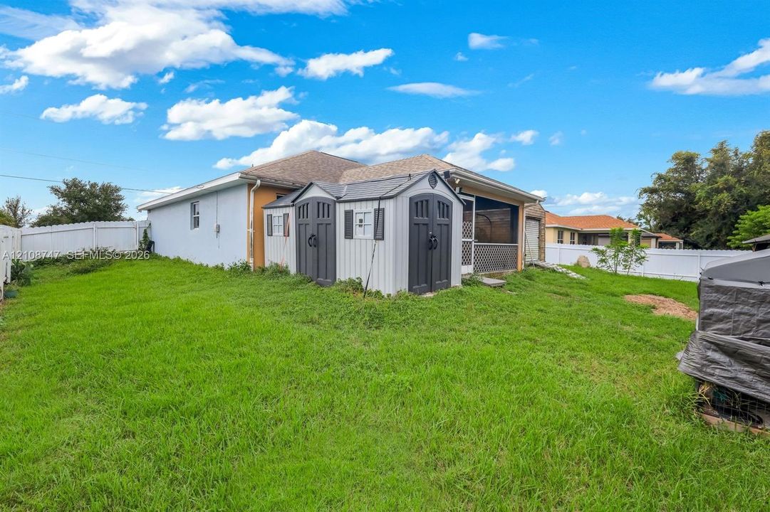 Backyard featuring a sprawling lawn, white vinyl fencing, and a covered rear patio