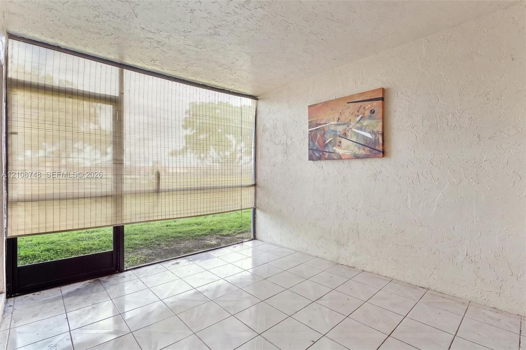 Enclosed space featuring ceramic tile flooring, textured wall finishes, and floor-to-ceiling glass paneling with a door