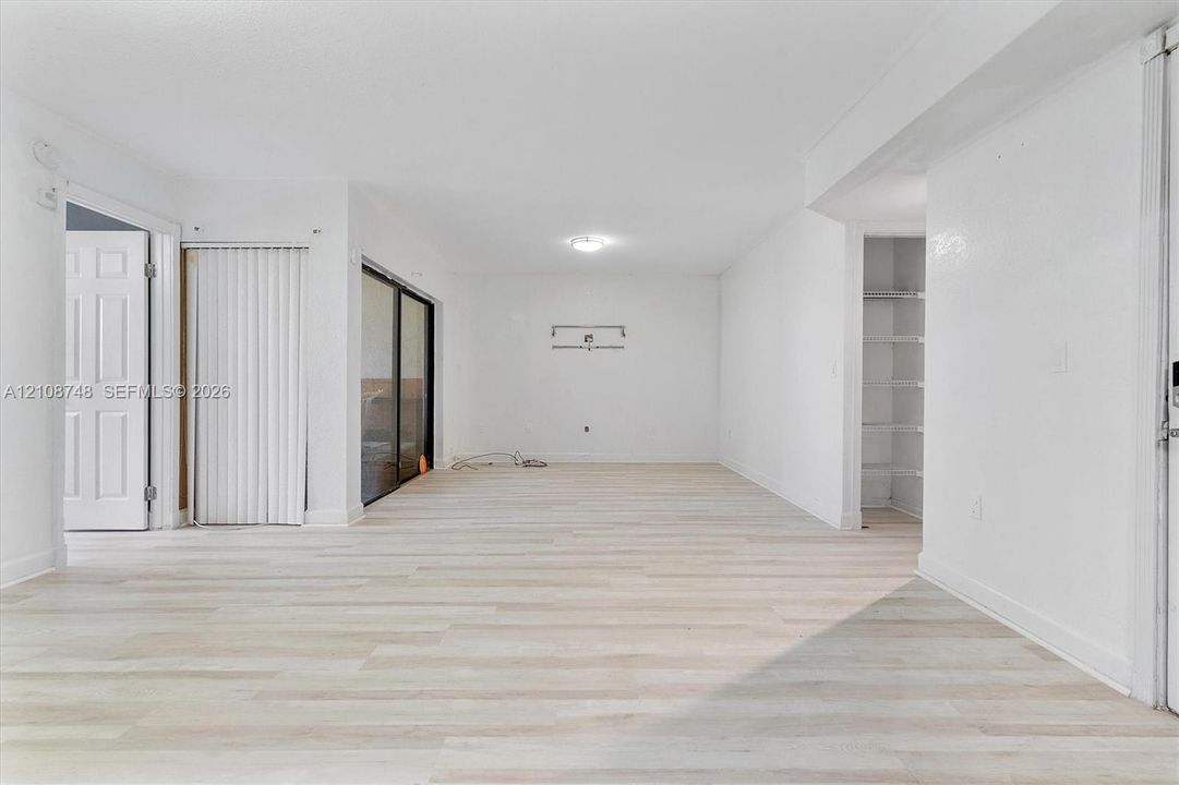 Light-toned wood-finish flooring, sliding glass doors with vertical blinds, and built-in shelving