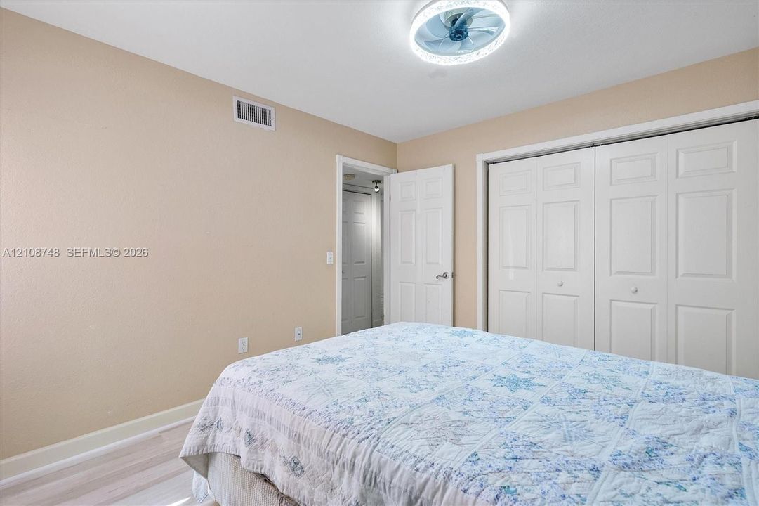 Room featuring wood-finish flooring, dual-panel closet doors, and a contemporary ceiling fan with integrated lighting