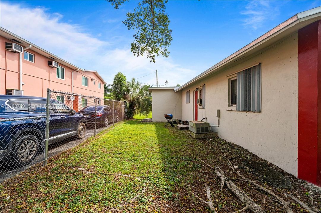 Exterior grounds featuring a grass lawn, chain-link fencing, and stucco siding
