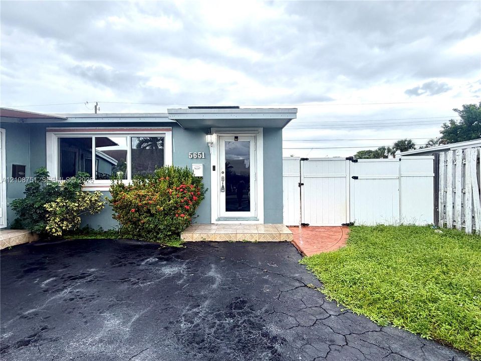 Exterior featuring a covered entryway, tiled porch, dual-pane windows, and white vinyl privacy fencing