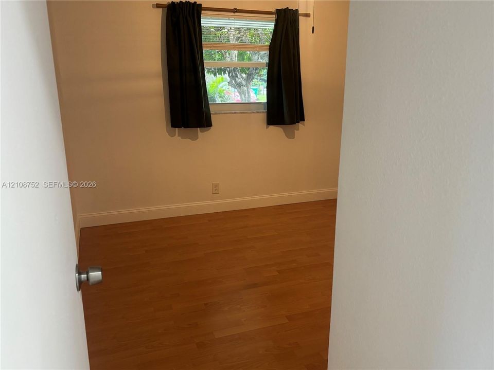 Room featuring wood-finish flooring, neutral-toned walls, and a horizontal sliding window