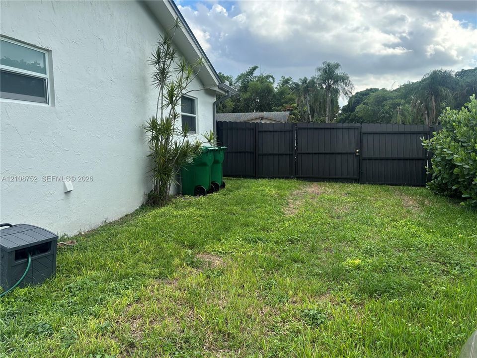 Rear exterior featuring a smooth stucco finish and a dark-toned vertical privacy fence