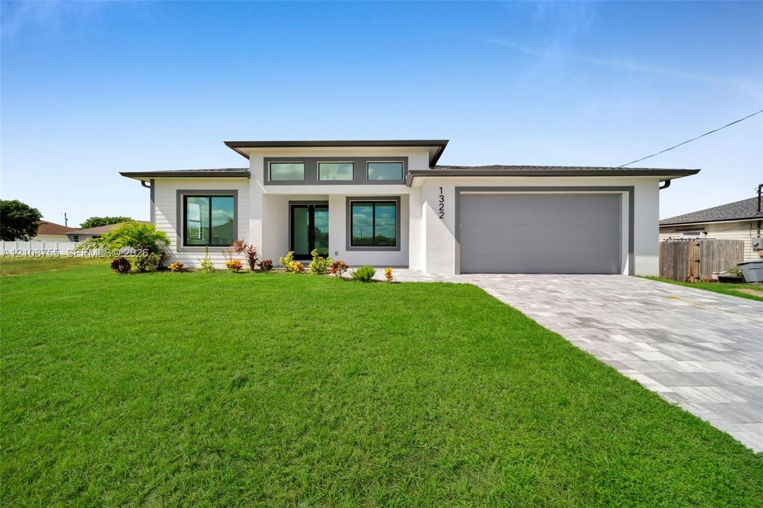 Contemporary single-story exterior featuring white siding, a paved driveway, a multi-paneled double front door, clerestory windows, and a shingled hip roof