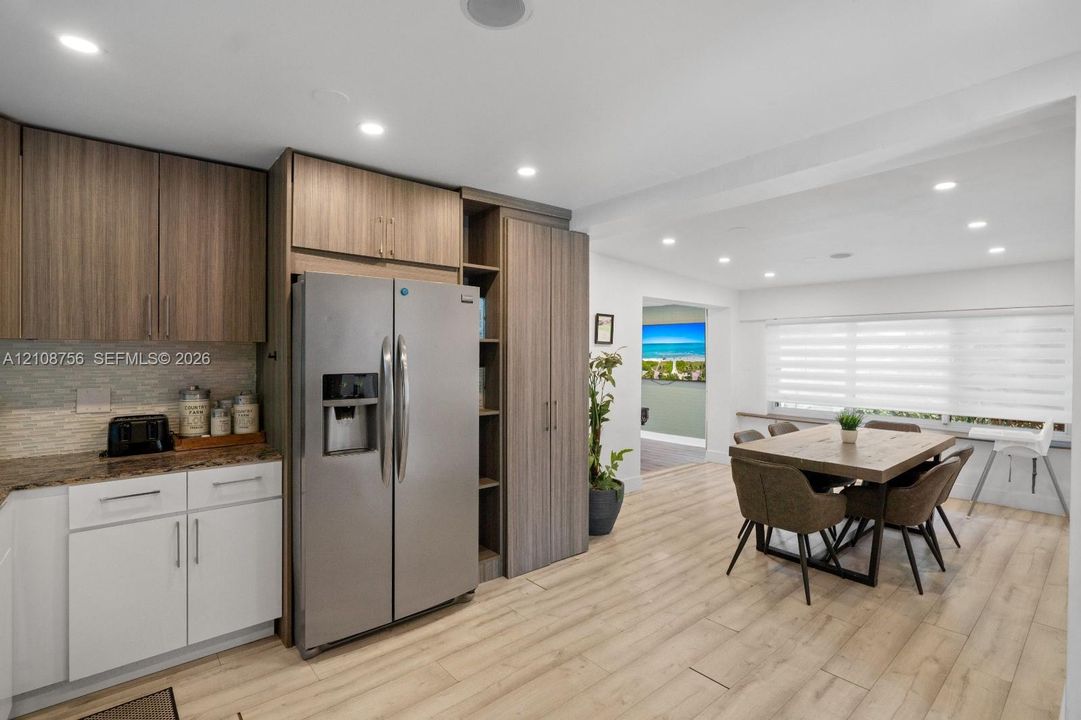 Kitchen featuring wood-finish cabinetry, stainless steel side-by-side refrigerator, stone-surfaced countertops, recessed lighting, and wood-finish flooring