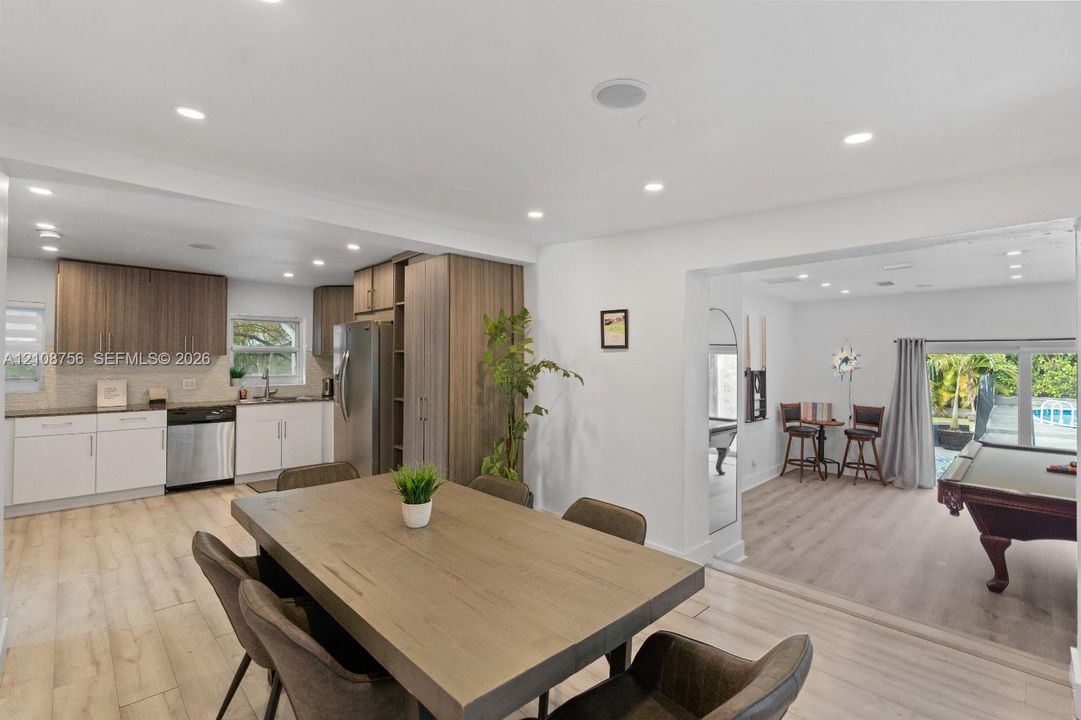 Open-concept kitchen featuring two-tone cabinetry, wood-finish flooring, recessed lighting, and stainless steel appliances