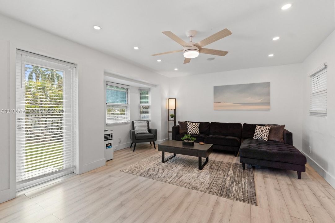 Interior space featuring wood-finish flooring, recessed lighting, a multi-blade ceiling fan with integrated light, a bay window, and a full-light glass door