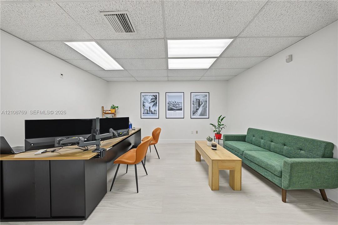 Room featuring light wood-finish flooring, white walls, and drop ceiling panels with integrated rectangular light fixtures