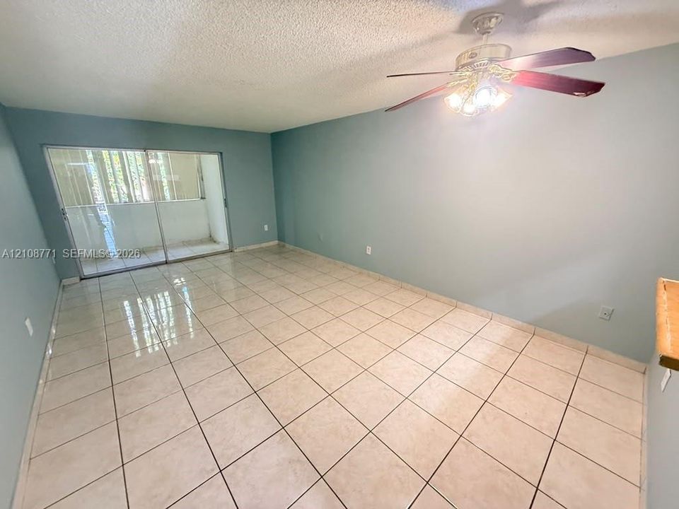 Neutral-toned ceramic tile flooring, sliding glass doors, and a ceiling fan with integrated lighting