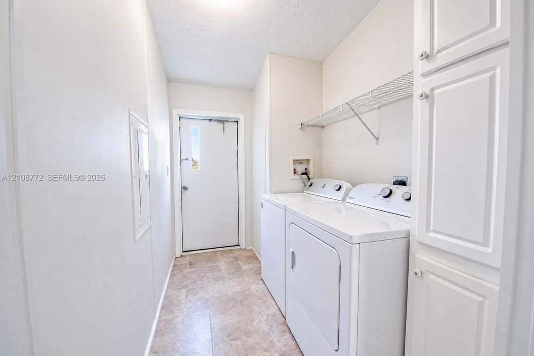 Laundry area featuring built-in cabinetry, wire shelving, and tile flooring