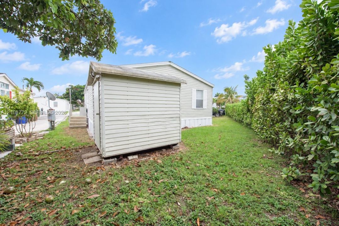 Exterior side yard featuring horizontal vinyl siding, a detached storage shed, and mature hedge landscaping
