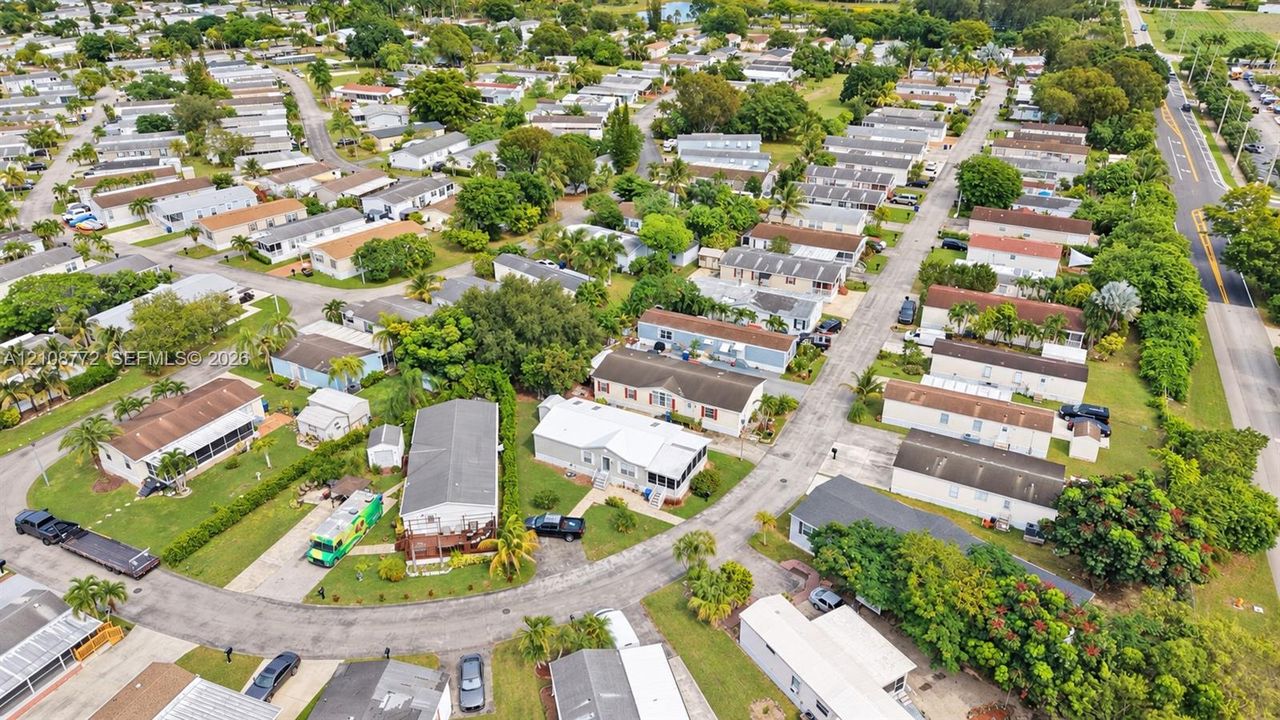 Aerial perspective of the residential development featuring paved streets, established landscaping with mature trees, and varying lot sizes