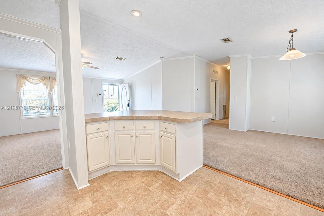 Kitchen peninsula featuring off-white cabinetry, neutral countertop, recessed lighting, carpeted flooring, and a pendant light fixture