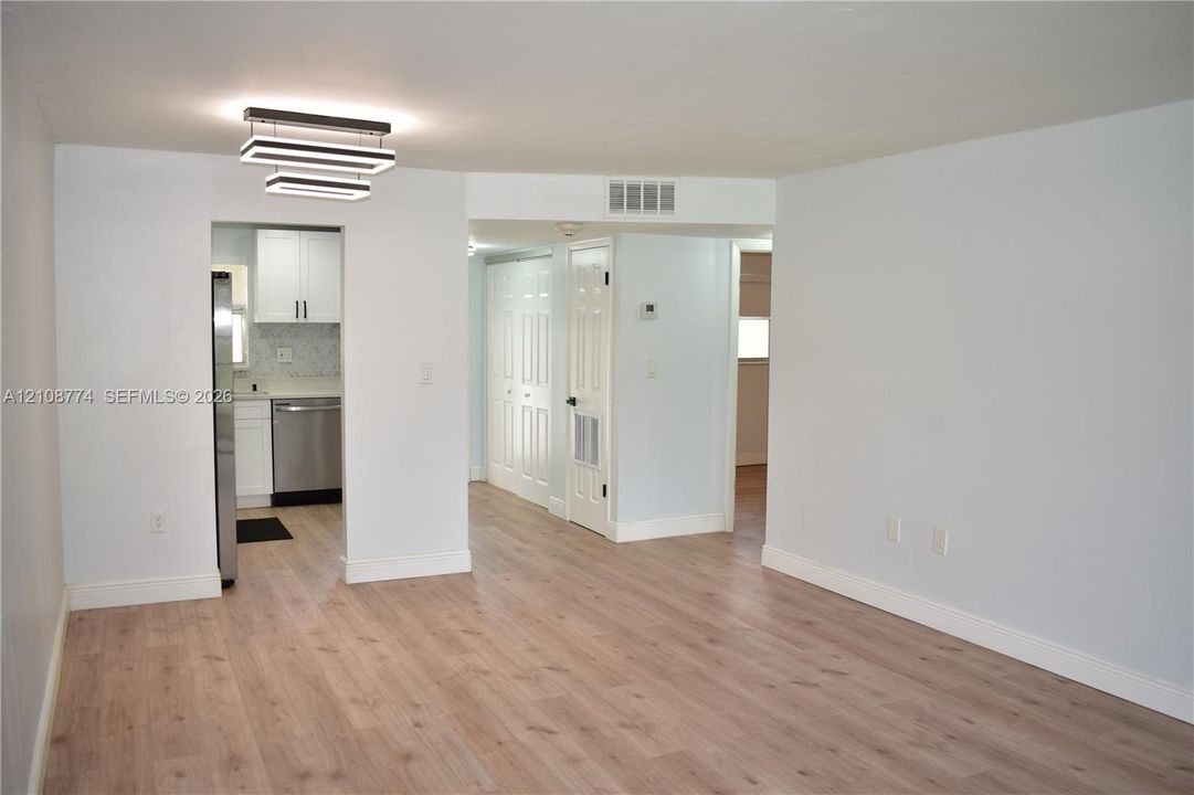 Wood-finish flooring, modern multi-tiered linear LED light fixture, white interior doors, and built-in closet cabinetry