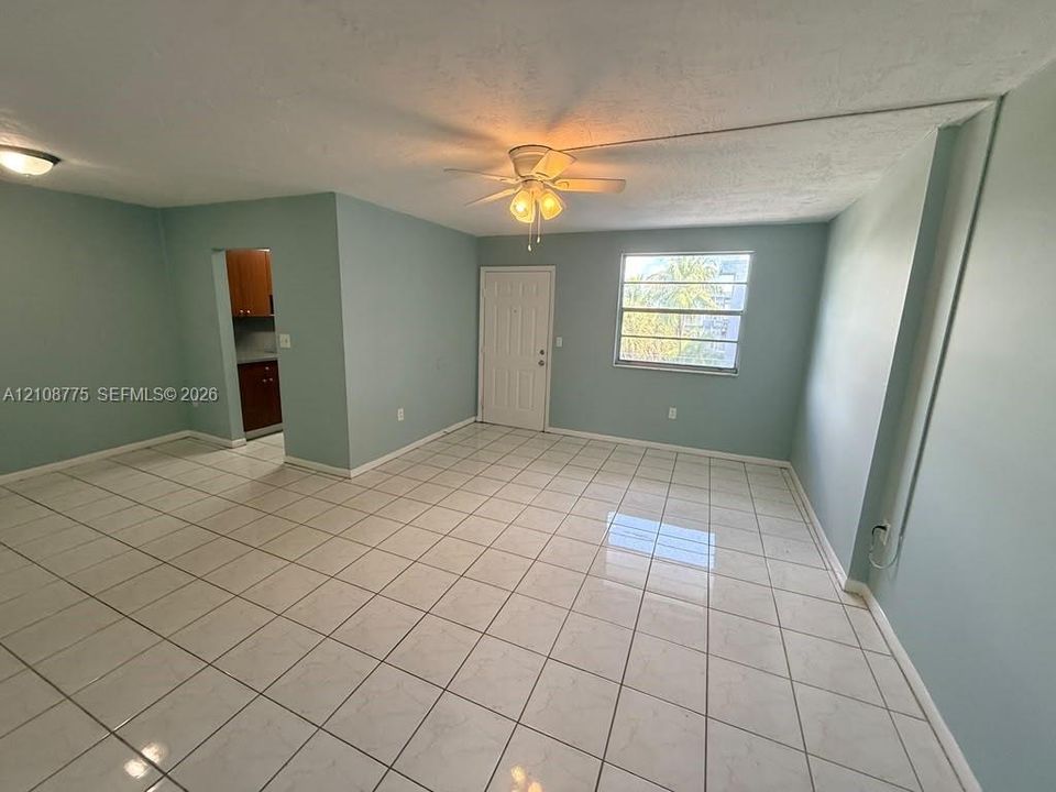 Interior space featuring large-format tile flooring, a multi-blade ceiling fan with integrated lighting, and an exterior entry door