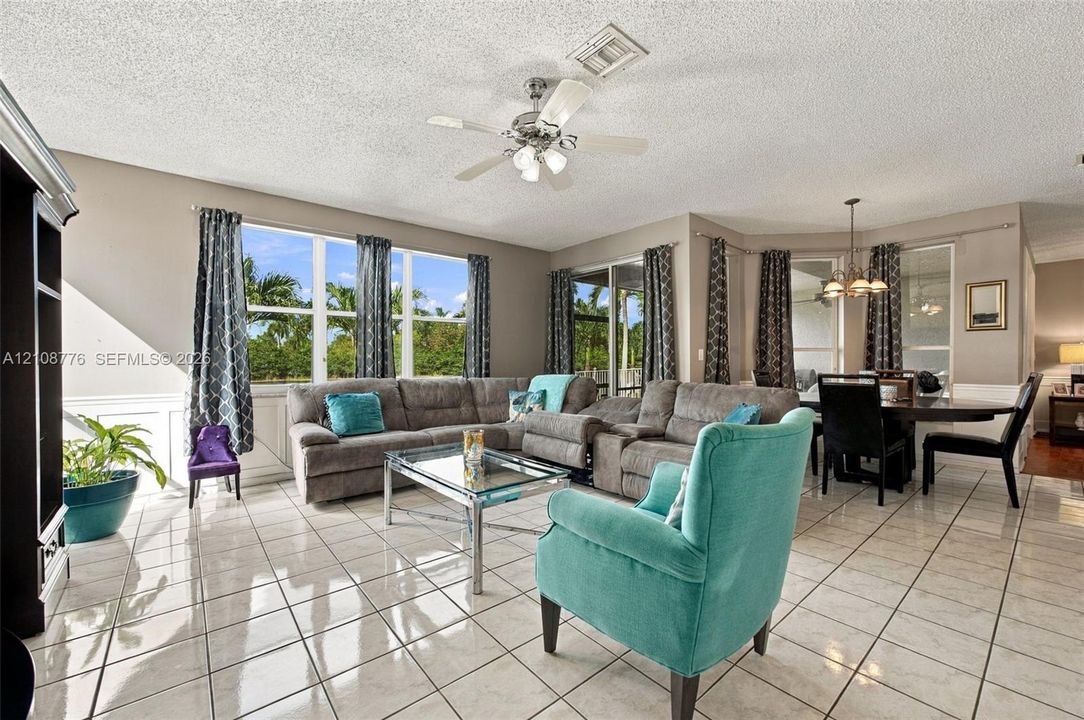 Light-filled living area featuring large multi-panel windows, ceramic tile flooring, built-in shelving, and a ceiling fan with integrated lighting
