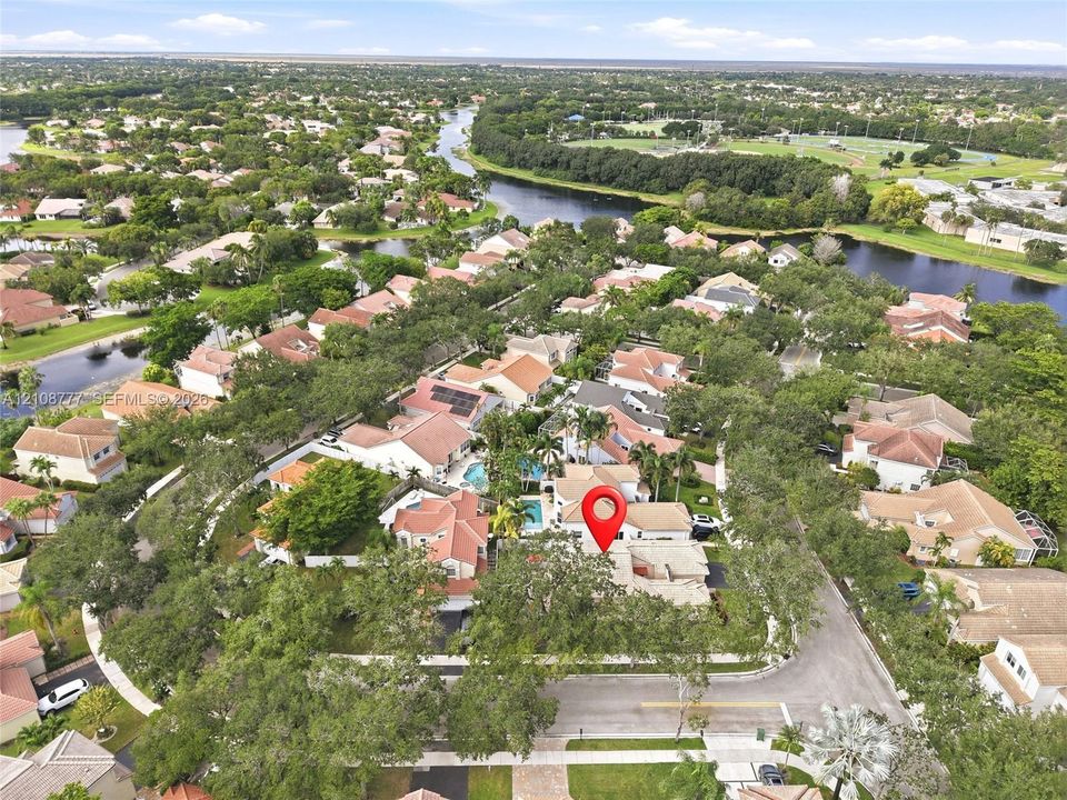 Aerial perspective featuring mature trees, a private swimming pool, and residential surroundings