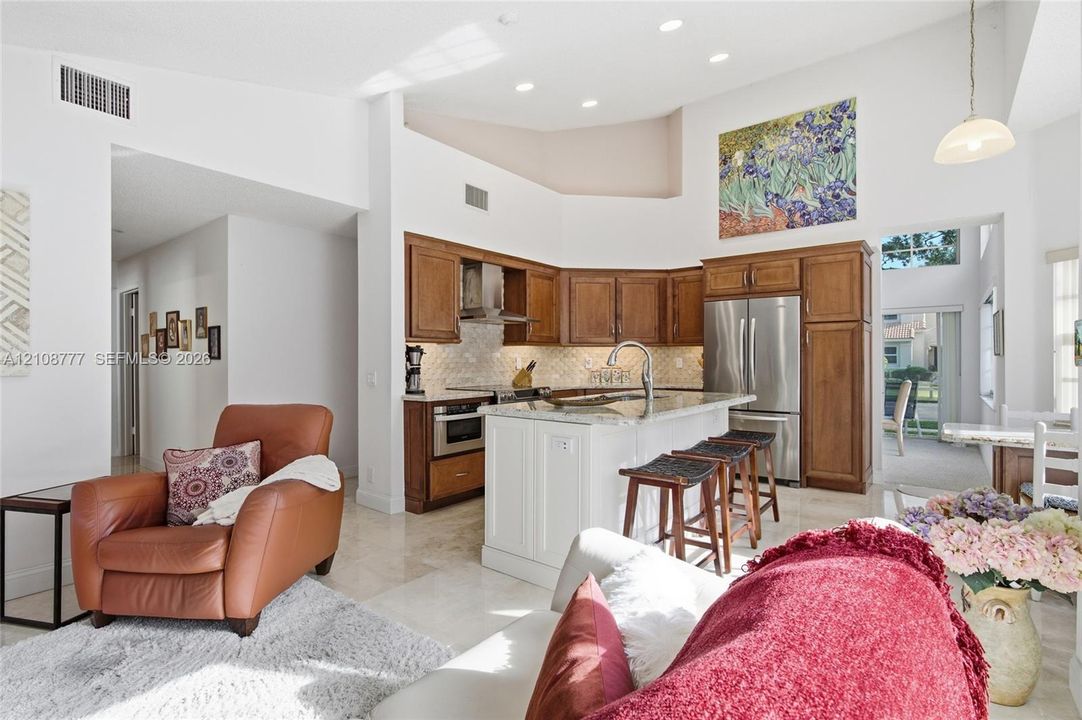 Kitchen featuring vaulted ceilings, recessed lighting, stone-surface center island with seating, and wood-finish cabinetry