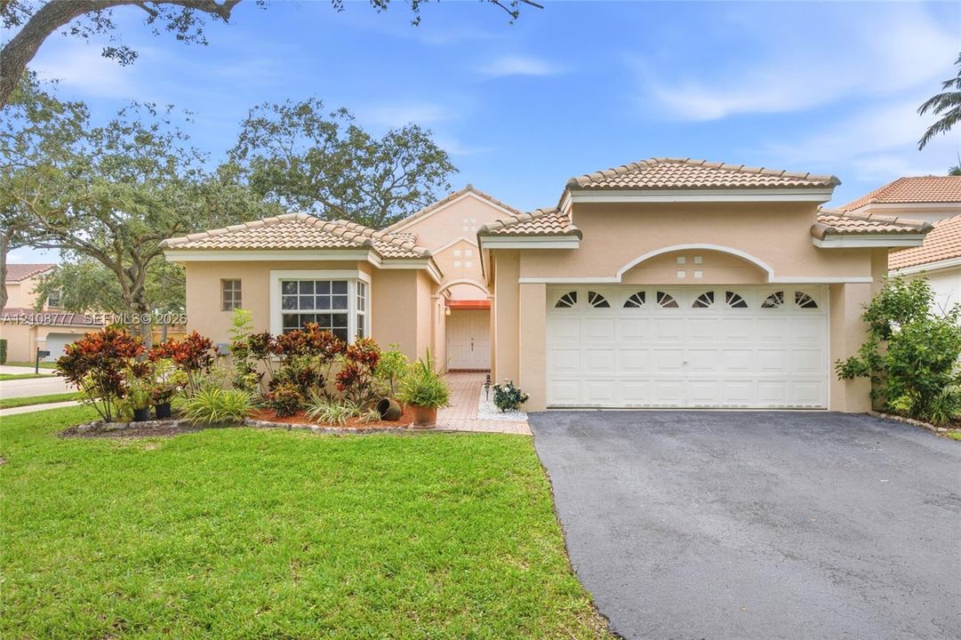 Single-story residence featuring a tile roof, stucco exterior, arched garage detailing, and a paved walkway leading to the entrance