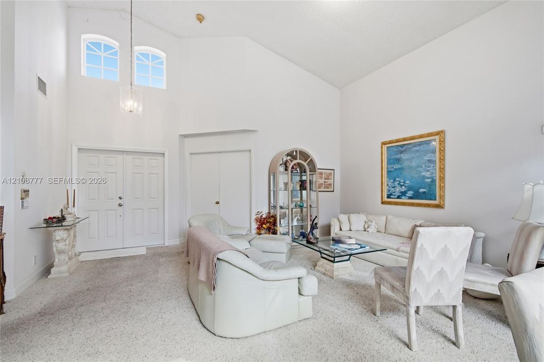 High ceilings featuring a multi-light pendant fixture, double entry doors, and arched transom windows