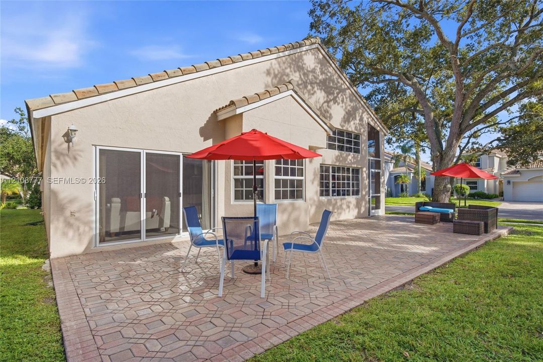 Rear exterior featuring a stamped concrete patio, stucco siding, multi-pane windows, and a sliding glass door