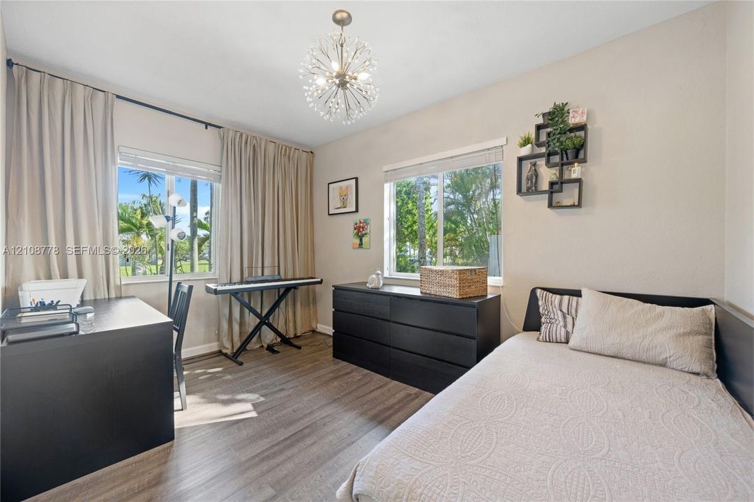 Wood-finish flooring, dual windows with exterior palm tree scenery, and a contemporary multi-arm spherical ceiling fixture
