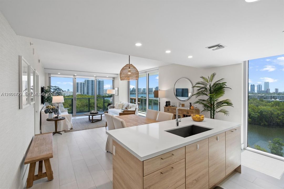 Open-concept kitchen featuring an island with wood-finish cabinetry, quartz countertops, and a rectangular undermount sink