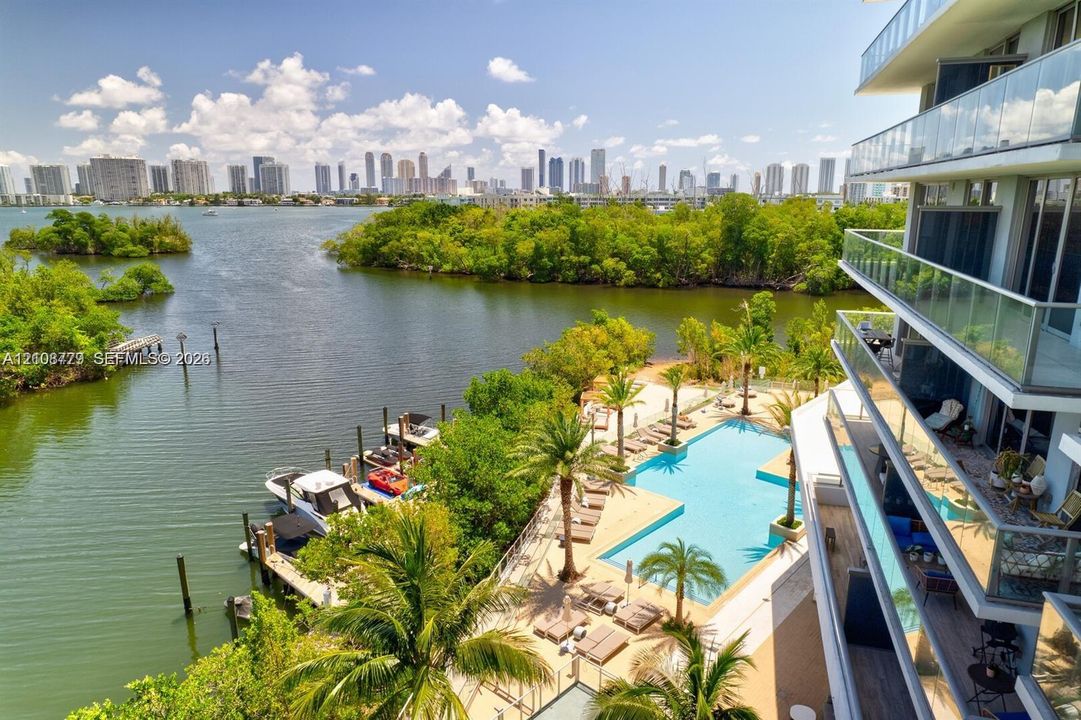 Waterfront high-rise building featuring glass-paneled balconies, a multi-level swimming pool, and private boat slips