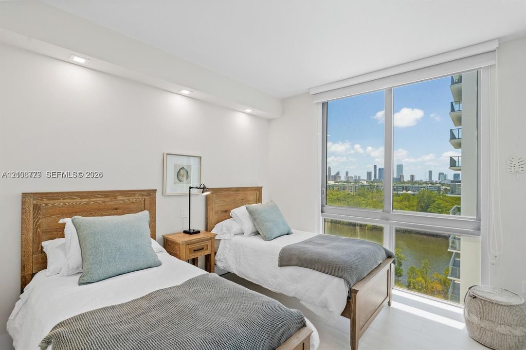 Floor-to-ceiling windows featuring urban and water scenery, recessed ceiling lighting, and smooth-finish flooring