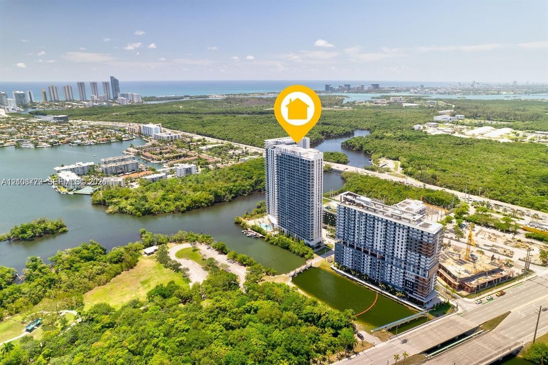 High-rise tower positioned among waterfront inlets, expansive green space, and surrounding coastal landscape