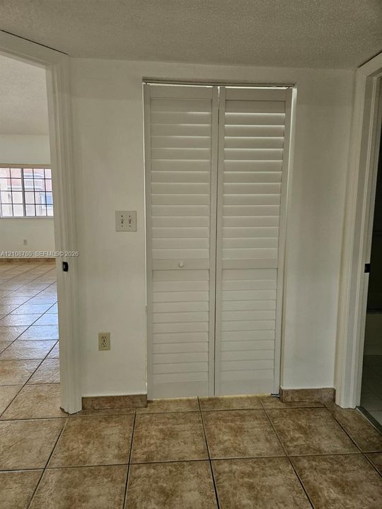 White louvered bi-fold doors and neutral tile flooring