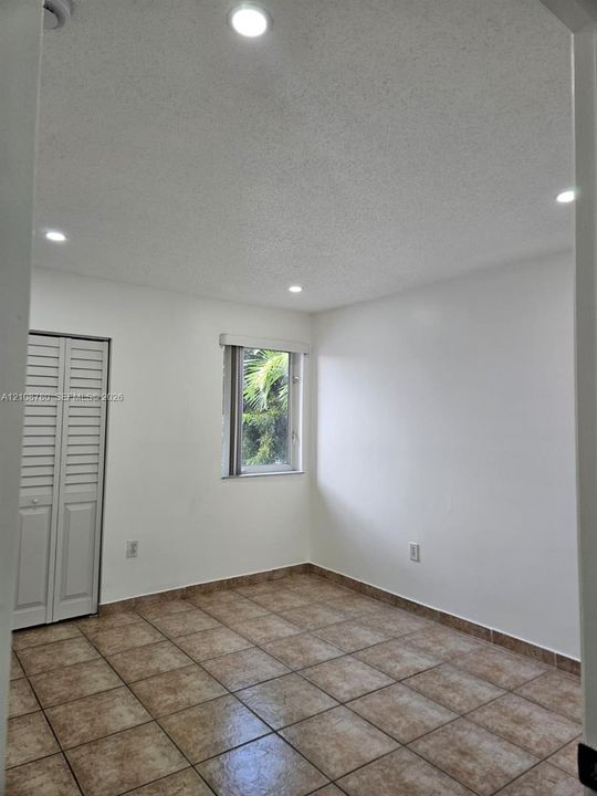 Interior space featuring tile flooring, recessed ceiling lighting, a single window, and a white louvered closet door