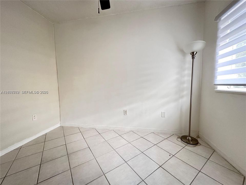 Neutral wall color, light-colored tile flooring set on a diagonal, and dual-layered window blinds