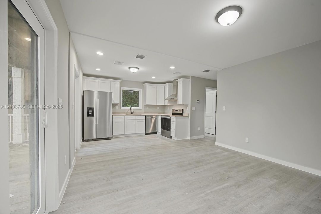 Kitchen featuring white cabinetry, stainless steel appliances, wood-finish flooring, recessed lighting, and a sliding glass door
